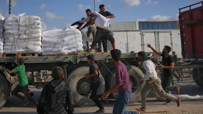 Palestinians grab sacks of flour from a moving truck carrying World Food Programme aid as it drives through Deir al-Balah in central Gaza, Nov. 15, 2025.