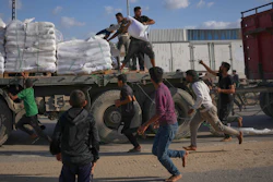 Palestinians grab sacks of flour from a moving truck carrying World Food Programme aid as it drives through Deir al-Balah in central Gaza, Nov. 15, 2025.