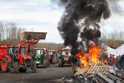 French farmers gather around a fire as they block the highway near Urt, southwestern France, to protest against a mass cull of cows ordered to contain the spread of a skin disease, Dec. 15, 2025.