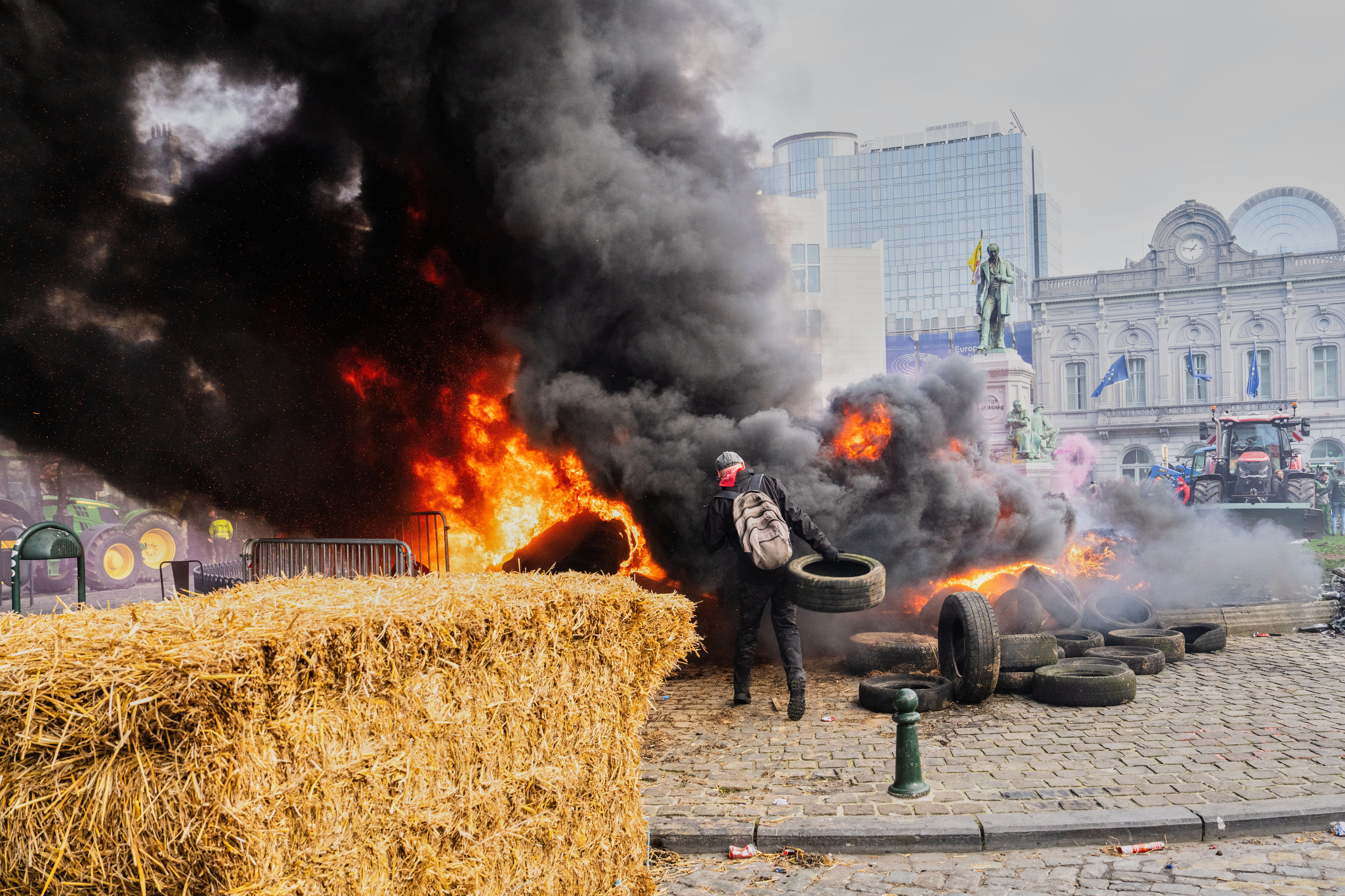 A protestor picks up tire to throw onto a fire during a demonstration outside the EU Summit meeting in Brussels, Dec. 18, 2025.