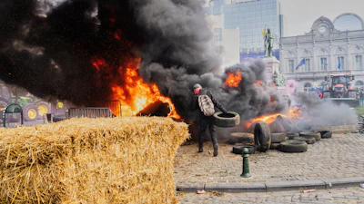 A protestor picks up tire to throw onto a fire during a demonstration outside the EU Summit meeting in Brussels, Dec. 18, 2025.