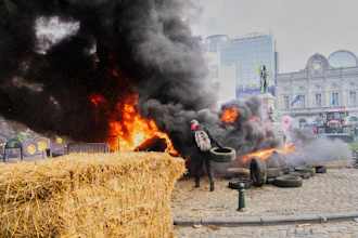 A protestor picks up tire to throw onto a fire during a demonstration outside the EU Summit meeting in Brussels, Dec. 18, 2025.