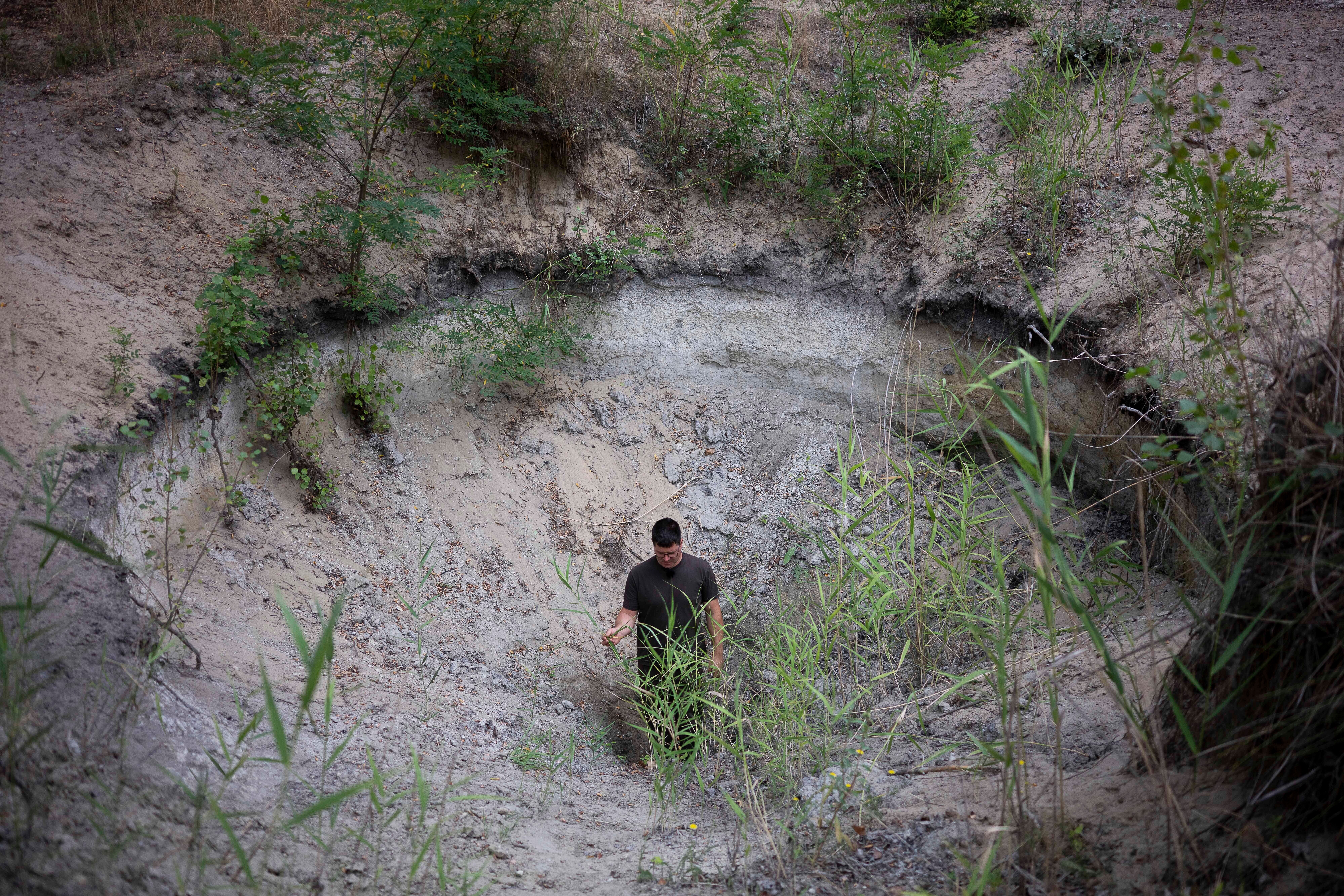 Oszk&aacute;r Nagyap&aacute;ti, farmer and member of the volunteer water guardians, stands in a hole in Kiskunmajsa, Hungary, July 29, 2025.