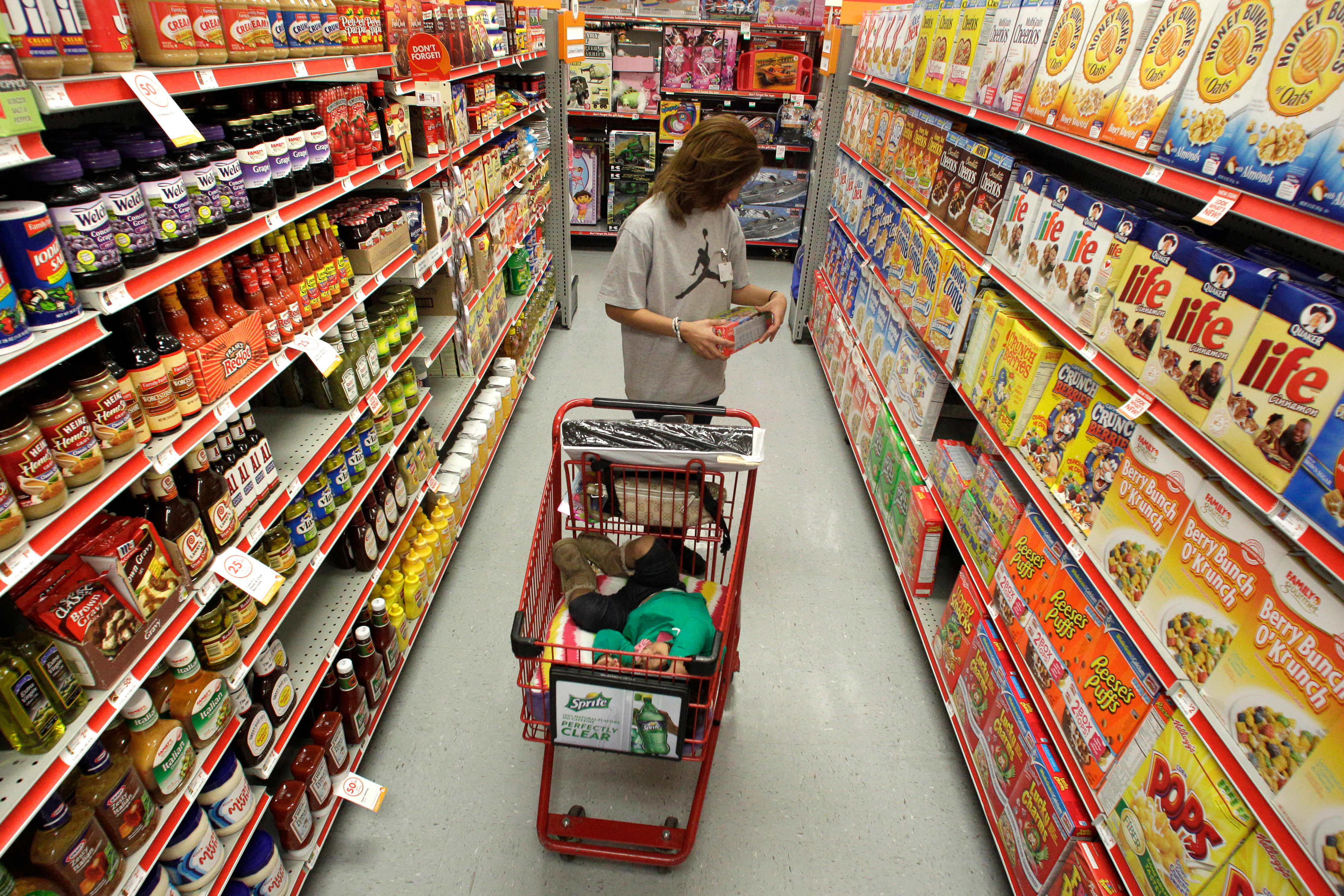 A woman looks at products in the aisle of a store as her daughter naps in the shopping cart, Waco, Texas, Dec. 14, 2010.