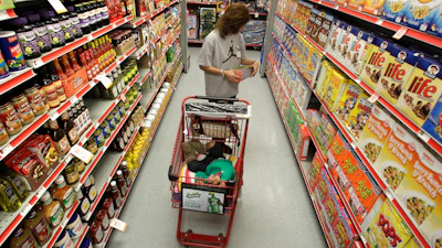 A woman looks at products in the aisle of a store as her daughter naps in the shopping cart, Waco, Texas, Dec. 14, 2010.