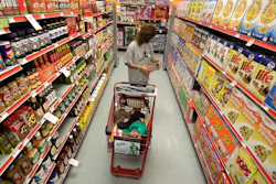 A woman looks at products in the aisle of a store as her daughter naps in the shopping cart, Waco, Texas, Dec. 14, 2010.