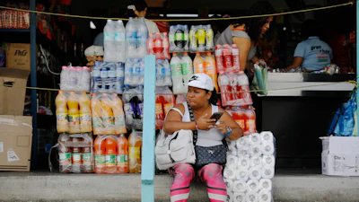 A woman sits in front of a store in the Petare neighborhood of Caracas, Venezuela, Jan. 7, 2026.