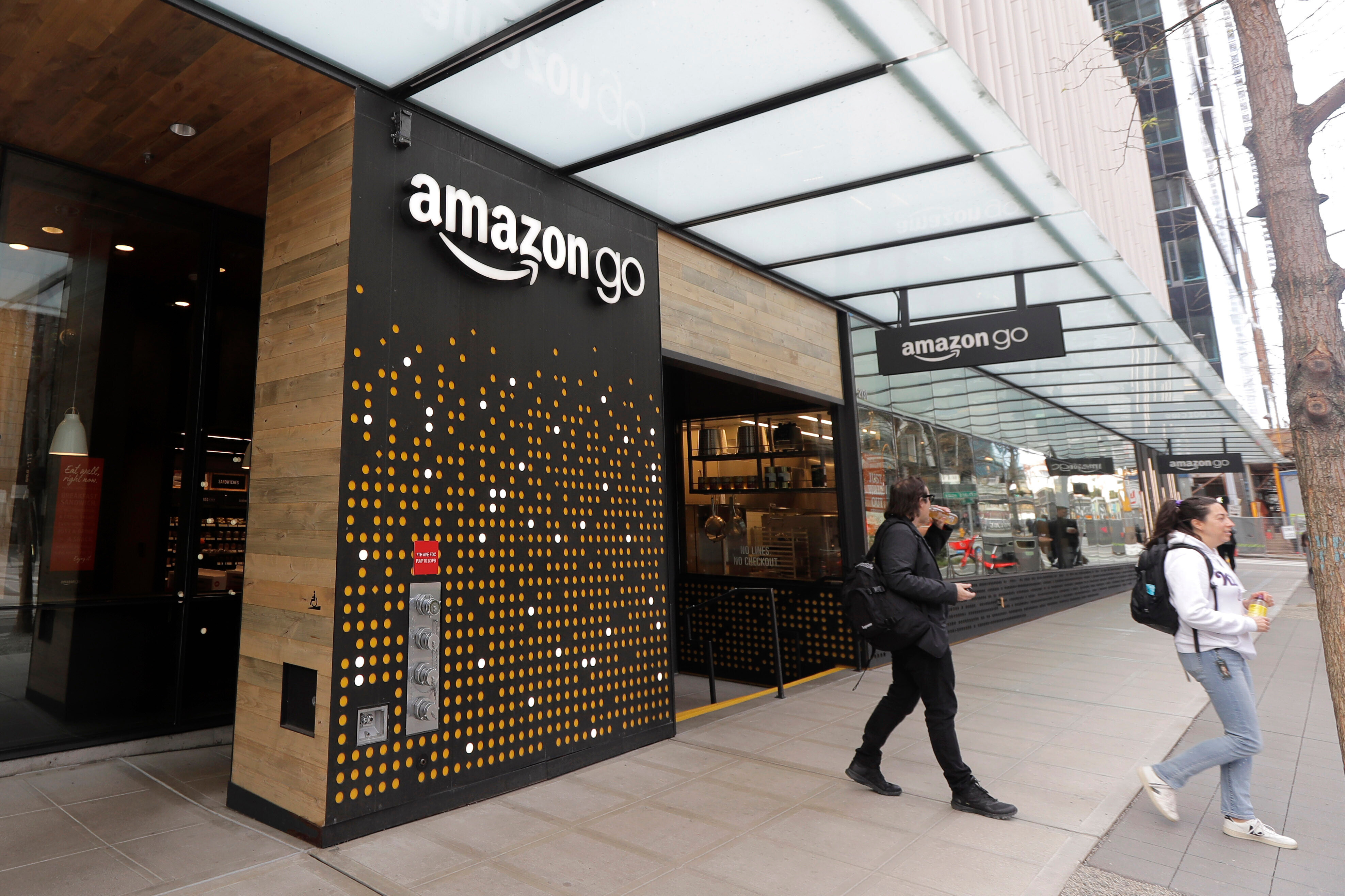 People walk out of an Amazon Go store in Seattle, March 4, 2020.
