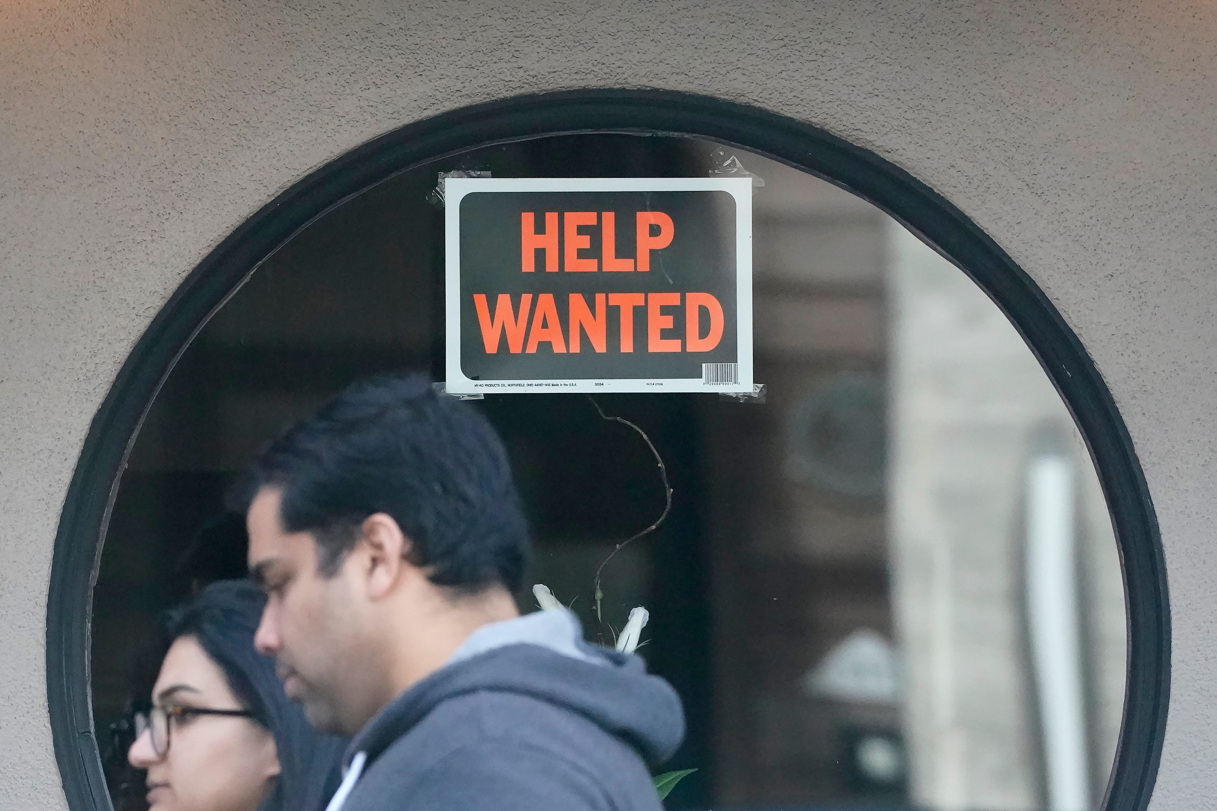 Pedestrians walk past a 'help wanted' sign posted on the door of a restaurant in San Francisco, April 18, 2023.