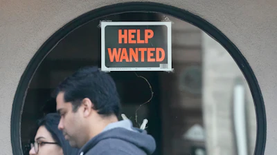 Pedestrians walk past a 'help wanted' sign posted on the door of a restaurant in San Francisco, April 18, 2023.