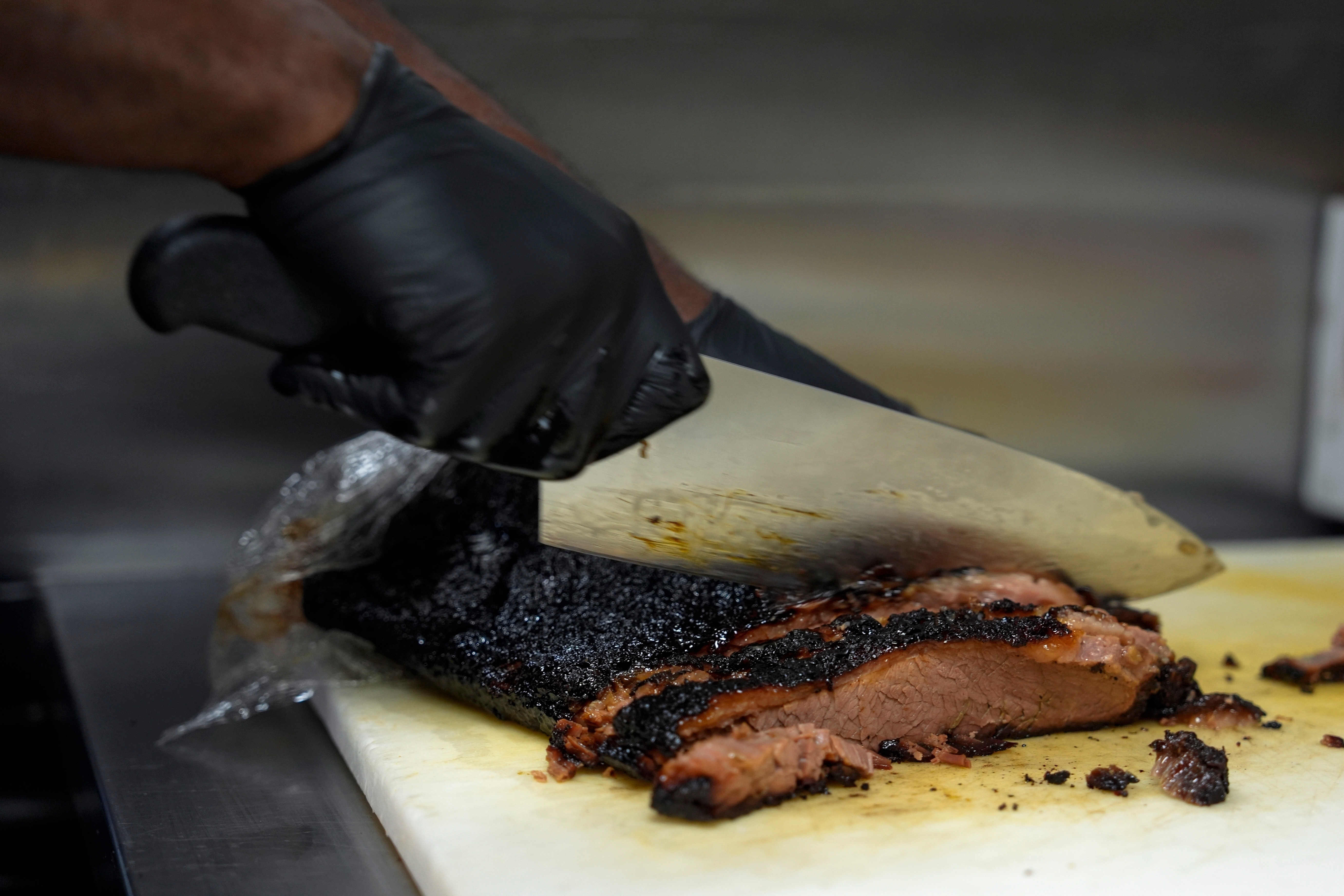 A line cook slices beef brisket at a barbecue restaurant in Cincinnati, June 12, 2024.