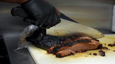 A line cook slices beef brisket at a barbecue restaurant in Cincinnati, June 12, 2024.
