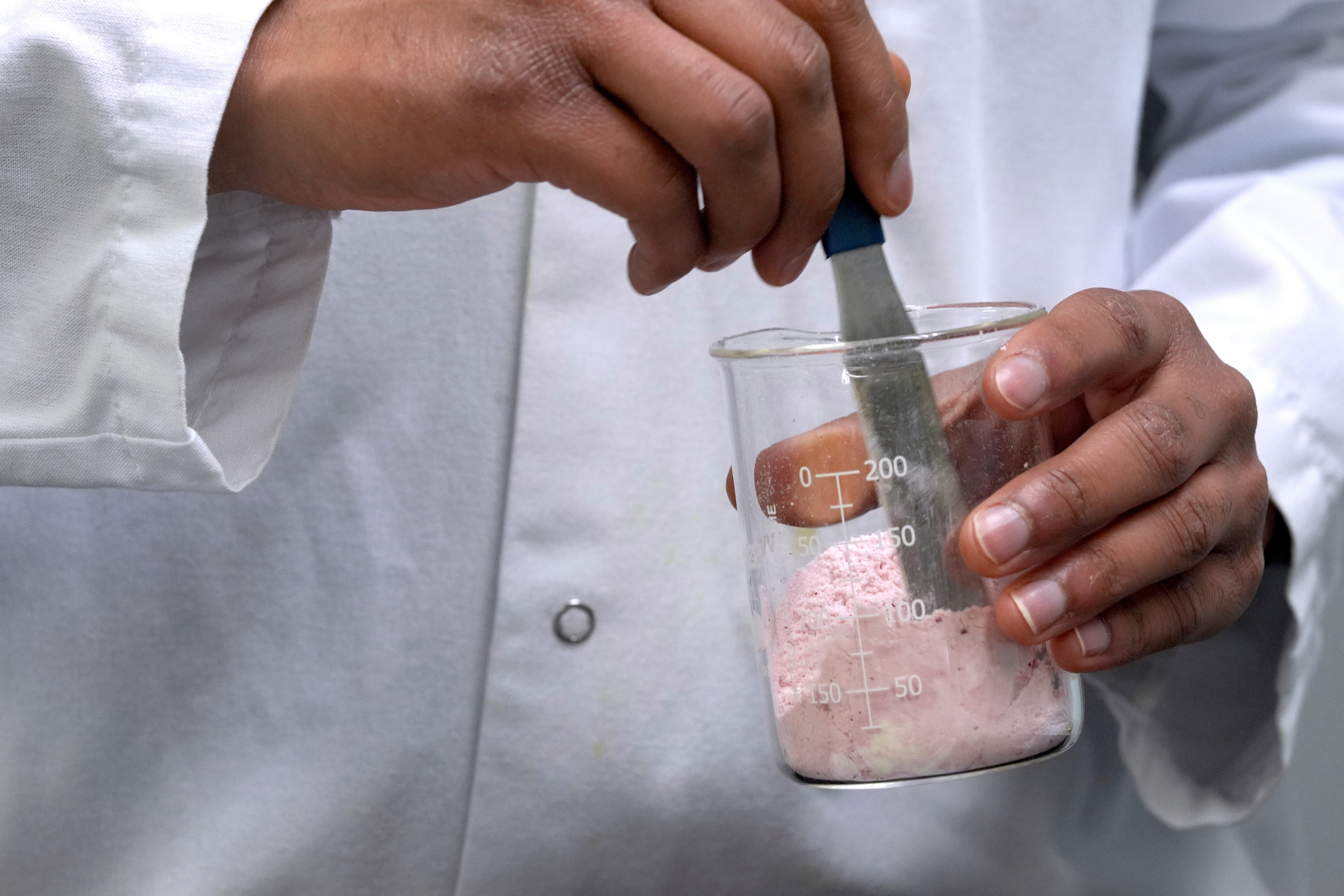 Applications scientist Anuj Bag mixes coloring with flour at Sensient Technologies Corp., a color additive manufacturing company, April 2, 2025, St. Louis.