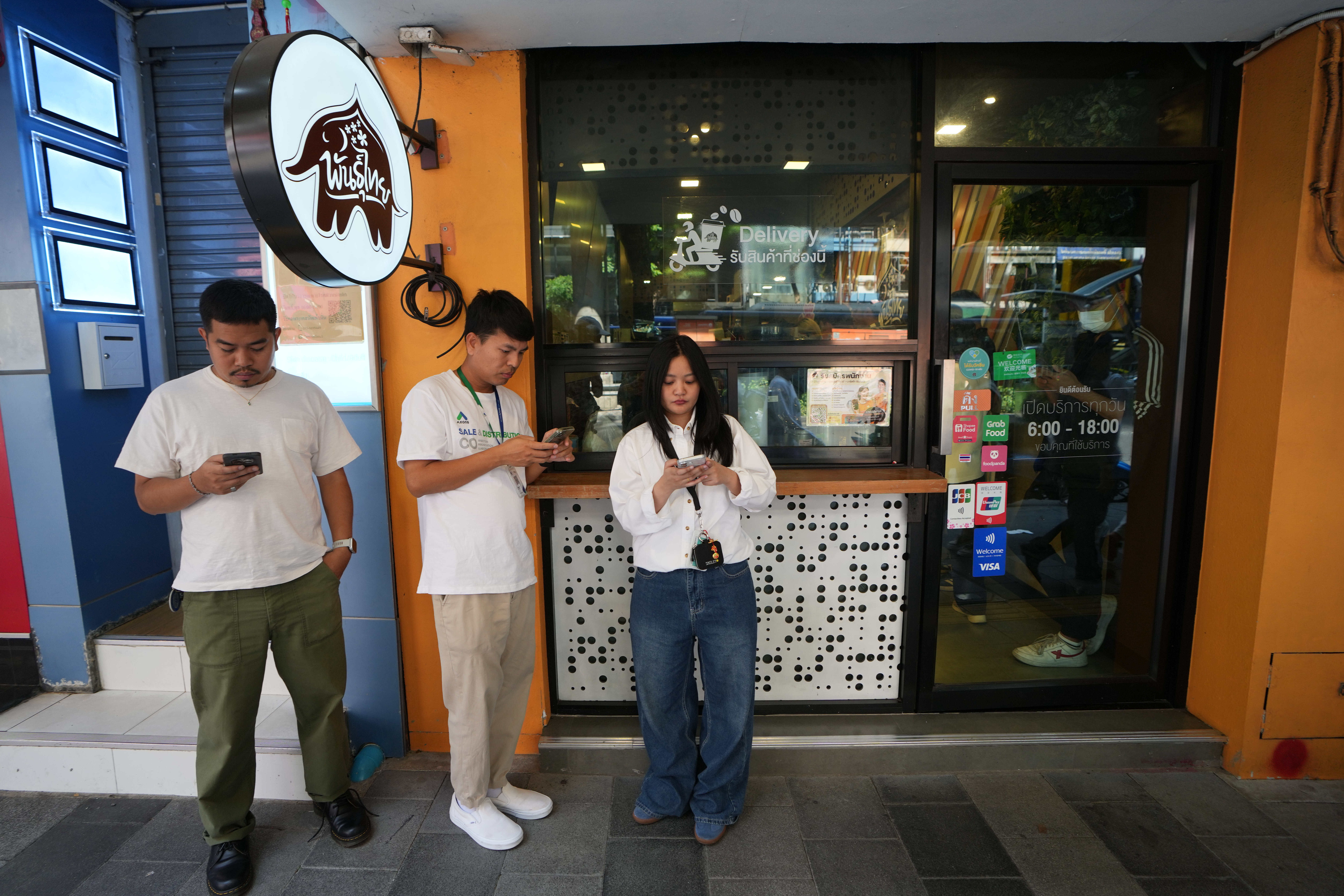 Customers wait for coffee outside a coffee shop in Bangkok, Feb. 11, 2026.