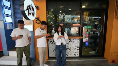Customers wait for coffee outside a coffee shop in Bangkok, Feb. 11, 2026.