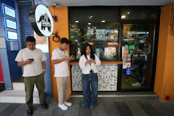Customers wait for coffee outside a coffee shop in Bangkok, Feb. 11, 2026.
