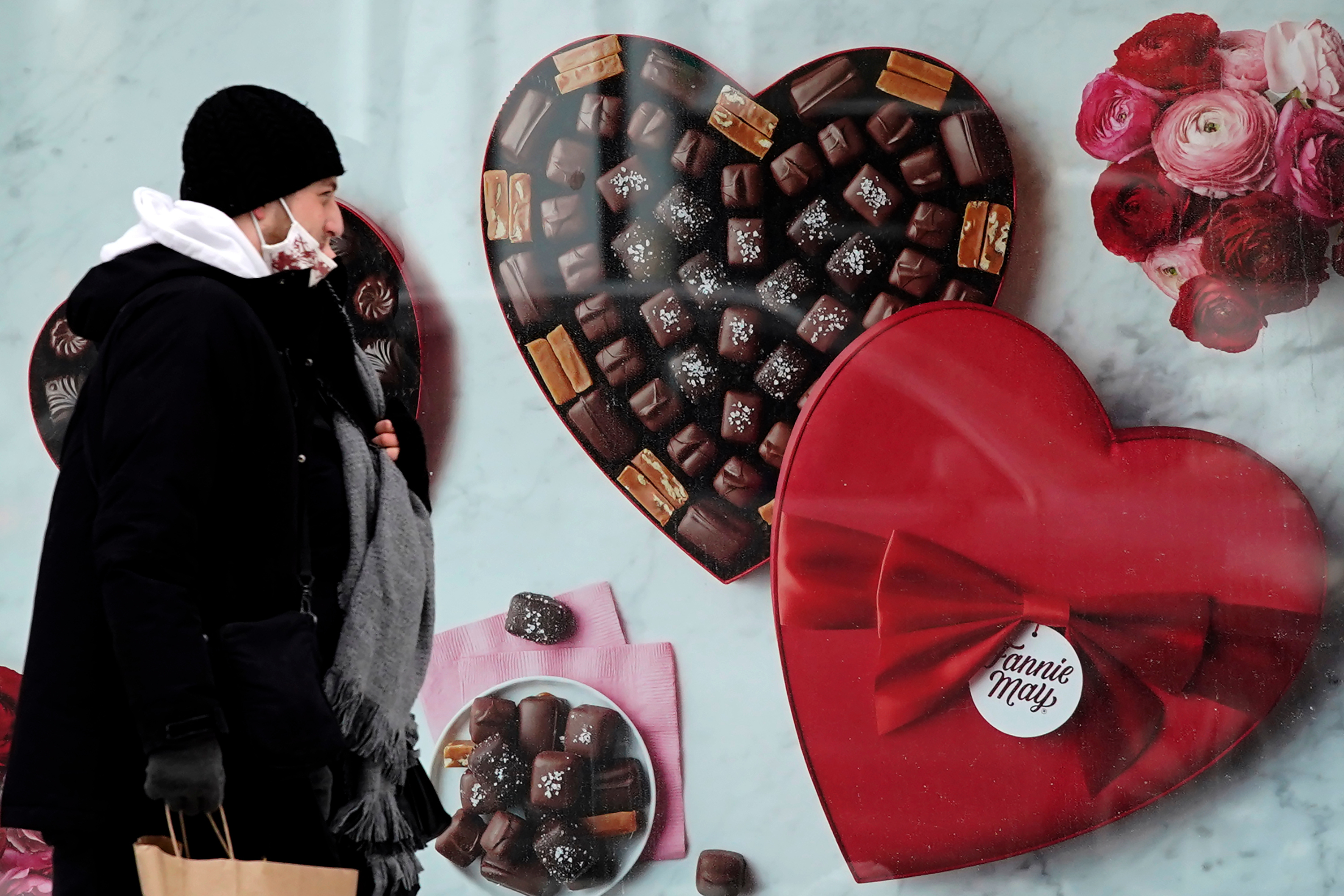 A man passes a Fannie May chocolate shop in Chicago, Feb. 14, 2021.