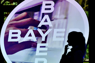 A woman walks in front of a Bayer AG logo at a news conference in Leverkusen, Germany, Feb. 27, 2020.
