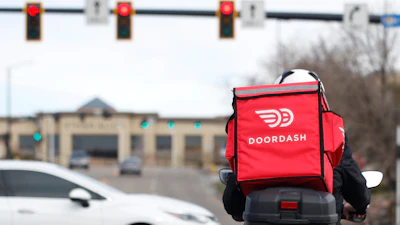 A food delivery rider waits for the traffic light to change, March 30, 2020, Lone Tree, Colo.