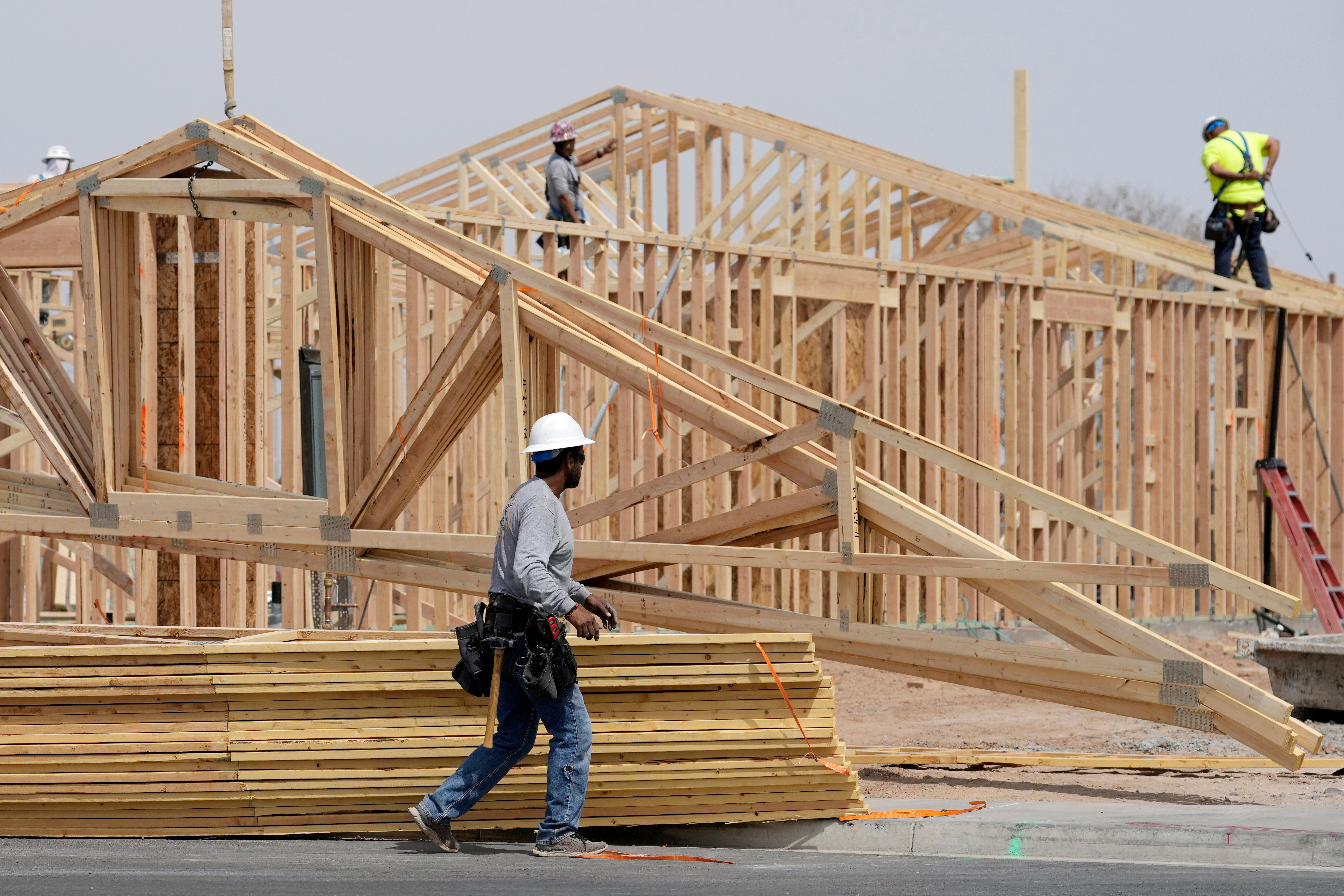Construction workers install a lumber roof at a new home build Tuesday, April 1, 2025, in Laveen, Ariz.