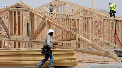 Construction workers install a lumber roof at a new home build Tuesday, April 1, 2025, in Laveen, Ariz.