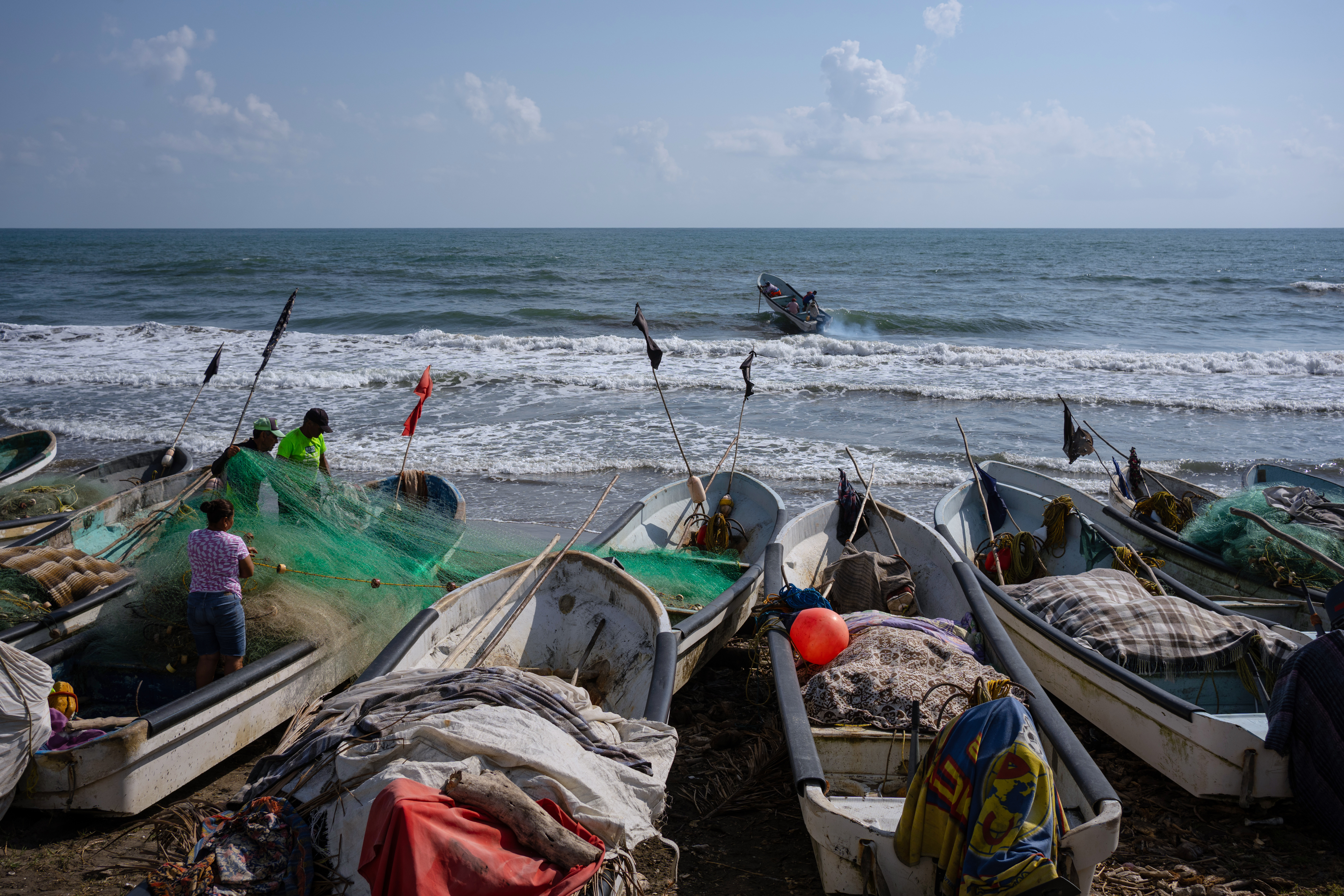 Fishermen untangle a net after suspending fishing trips because of an oil spill, Salinas, Mexico, March 26, 2026.