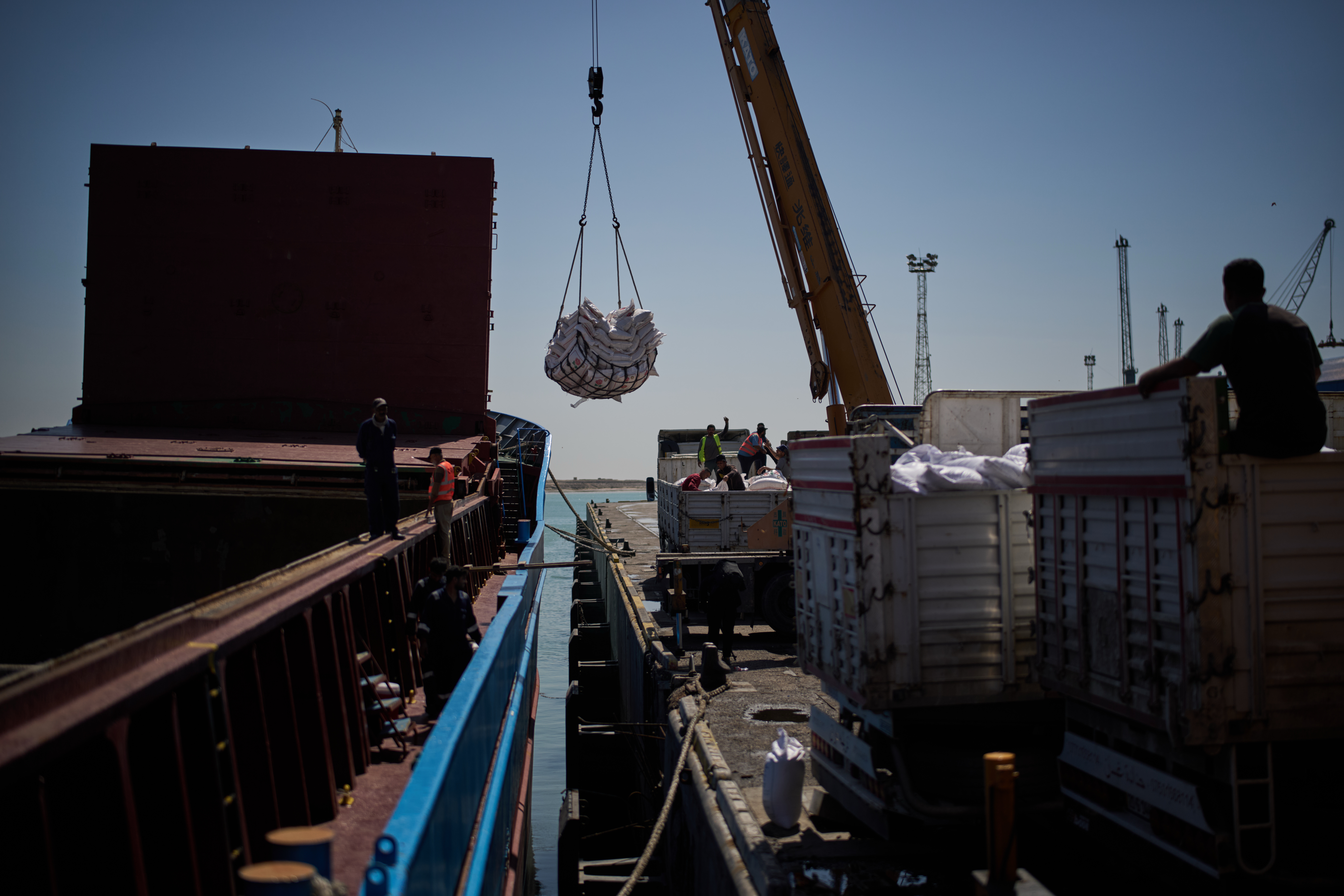 Workers offload cargo of rice from a feeder vessel into trucks at Umm Qasr Port, Iraq, March 27, 2026.