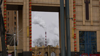 A chimney of a coal-fired power plant is visible near a residential complex in Datong, China, March 14, 2026.