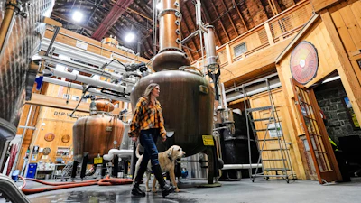 Meghan Ireland and her dog, Murphy, walk by one of the 750-gallon pot and column whiskey stills at the WhistlePig distillery Monday, April 6, 2026, in Shoreham, Vermont.