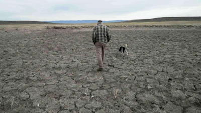 Philip Anderson walks across a dry stock pond in Walden, Colo., March 31, 2026.