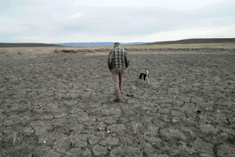 Philip Anderson walks across a dry stock pond in Walden, Colo., March 31, 2026.