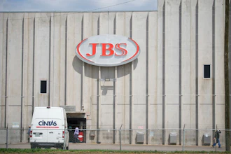 Employees walk in front of the entrance to the JBS meat processing plant, July 23, 2021, in Greeley, Colo.