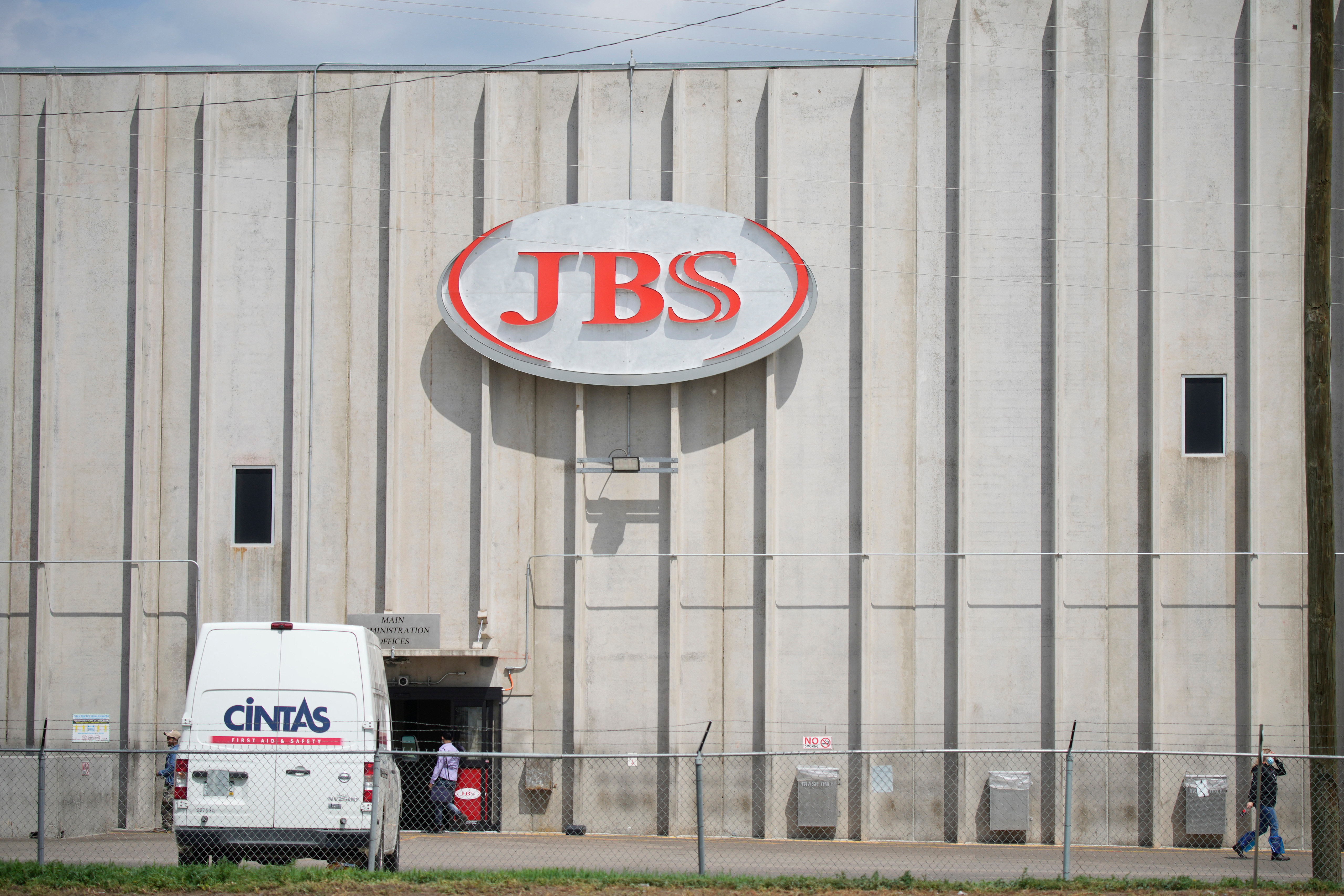 Employees walk in front of the entrance to the JBS meat processing plant, July 23, 2021, in Greeley, Colo.
