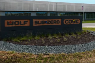 Wolf Subcero Cove outdoor monument sign with orange lettering in landscaped grounds before industrial building