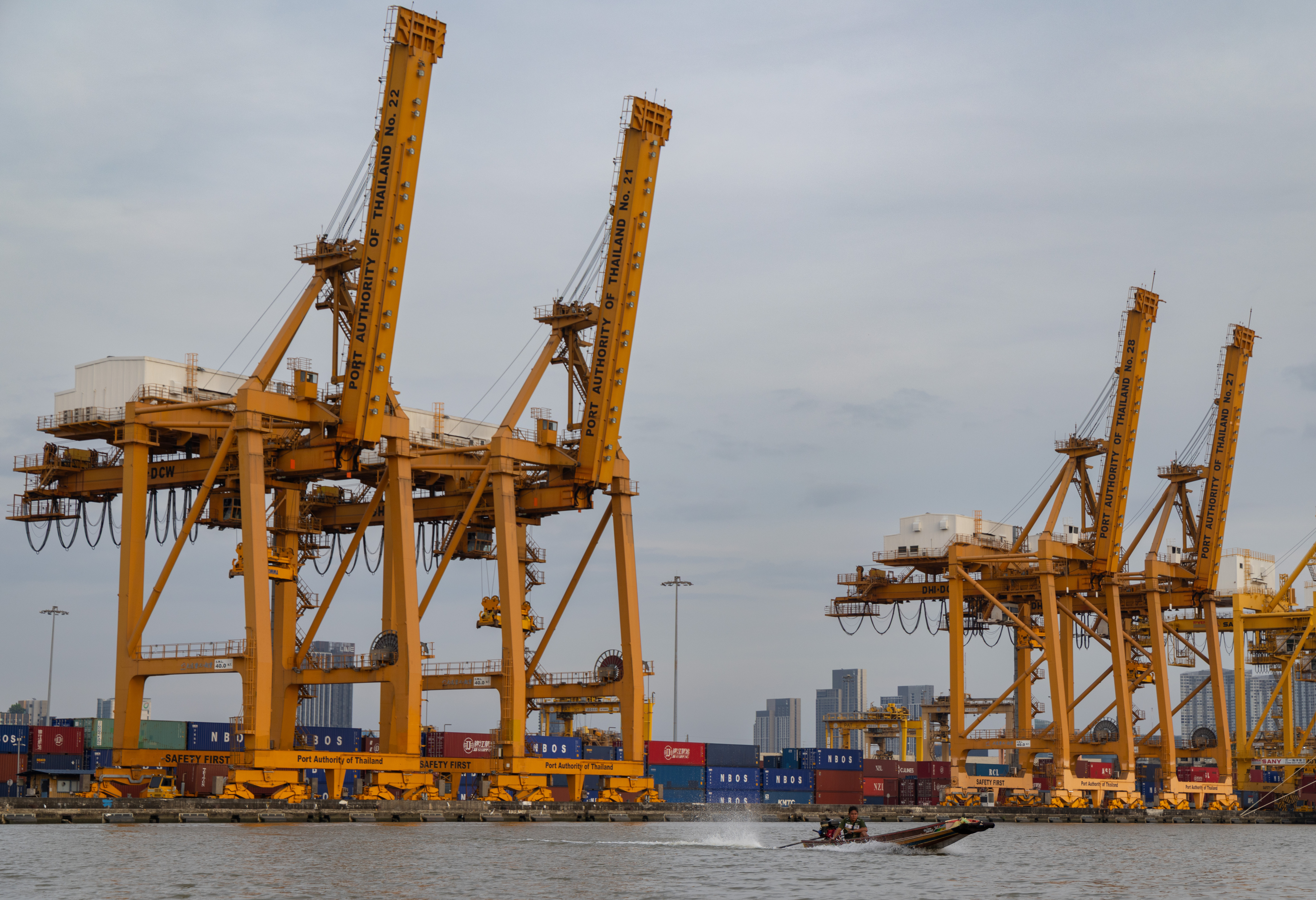 A small boat splashes past a row of ship-to-shore cranes at Khlong Toei Pier in Bangkok, Thailand, Jan 3, 2026.