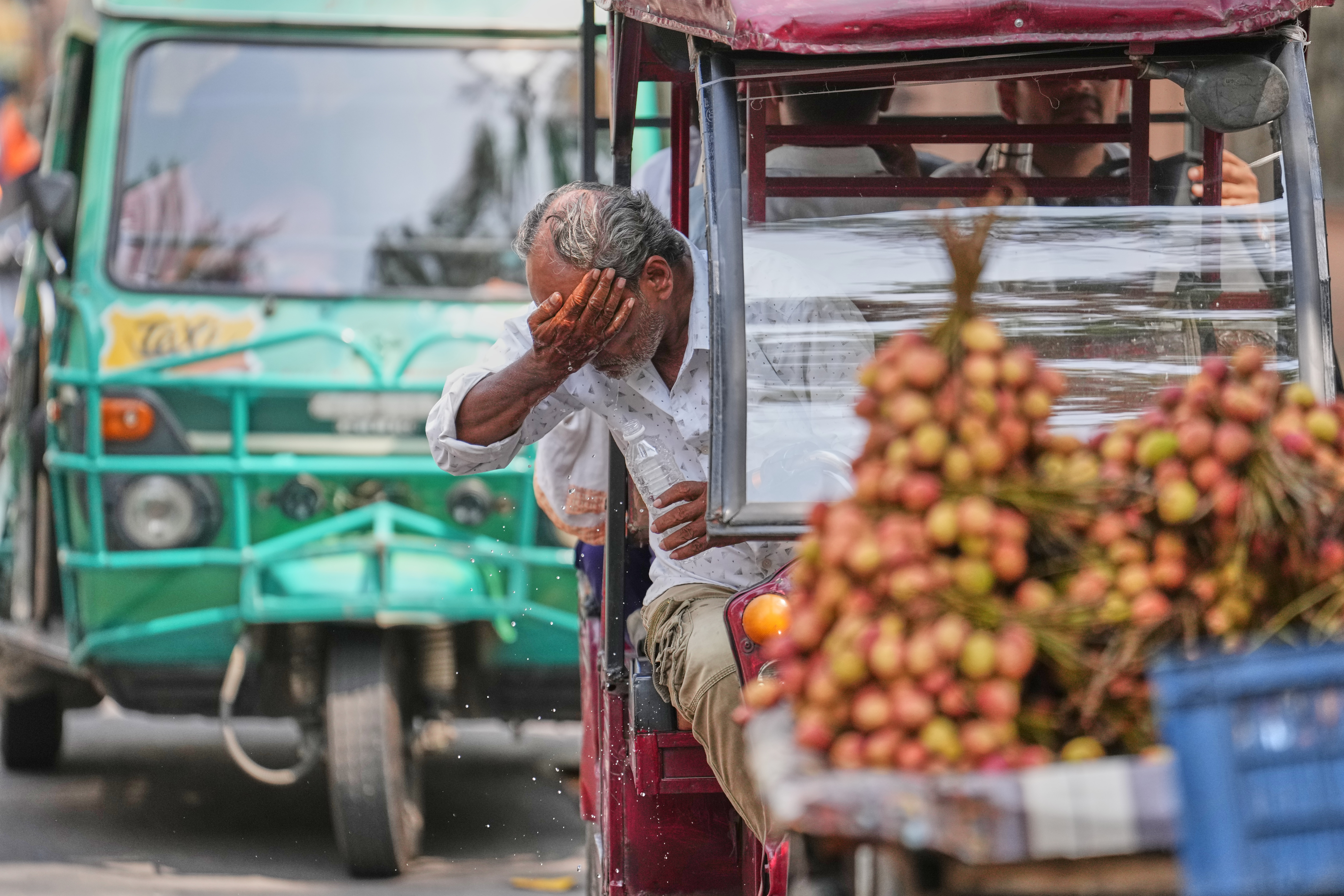 An electric rickshaw driver splashes water on his face to cool off under intense heat in Lucknow, India, May 20, 2026.
