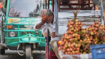 An electric rickshaw driver splashes water on his face to cool off under intense heat in Lucknow, India, May 20, 2026.