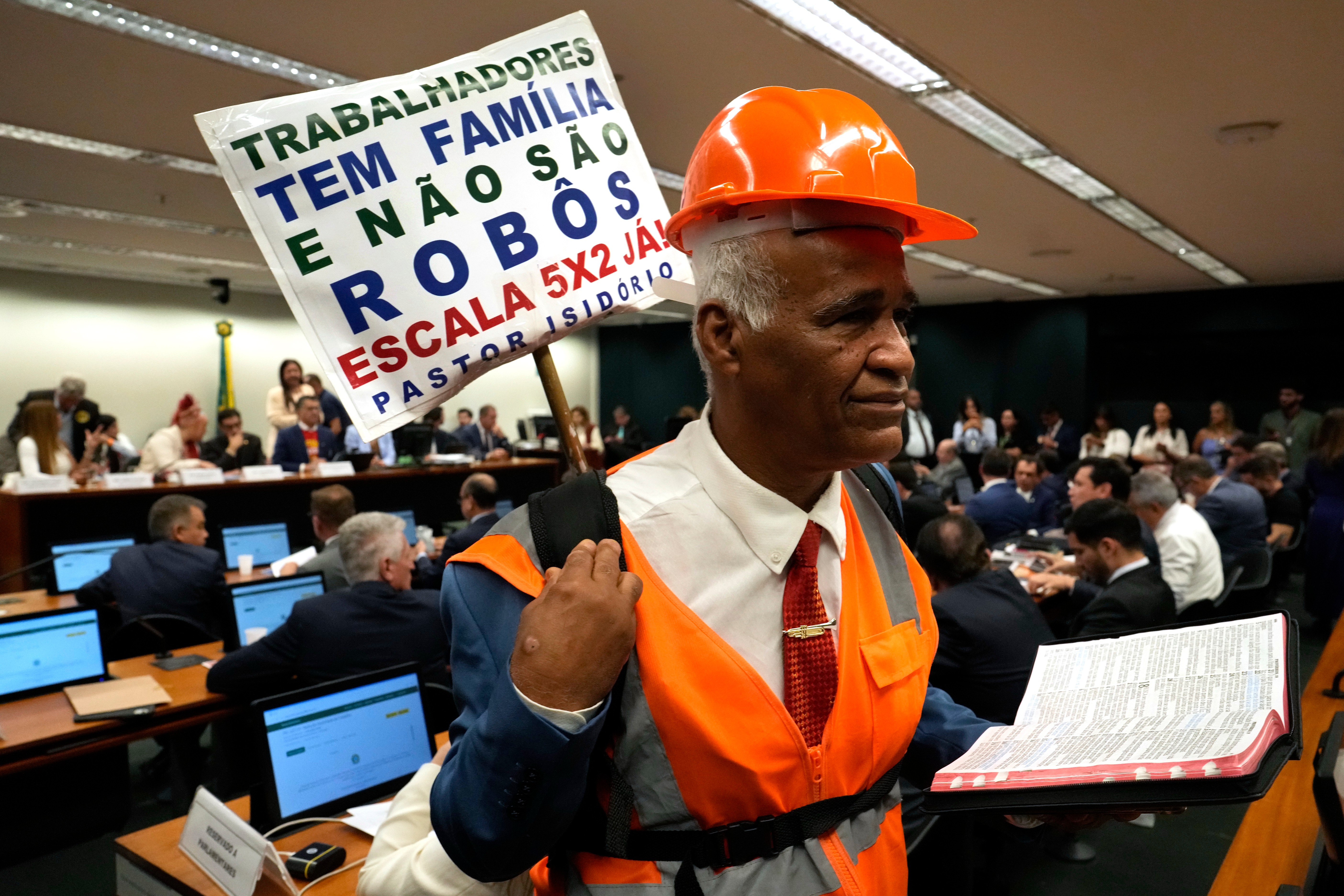 Lawmaker and Pastor Sargento Isidorio holds a sign supporting the end of Brazil's six-day workweek in the Chamber of Deputies, Brasilia, May 27, 2026.