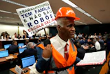 Lawmaker and Pastor Sargento Isidorio holds a sign supporting the end of Brazil's six-day workweek in the Chamber of Deputies, Brasilia, May 27, 2026.