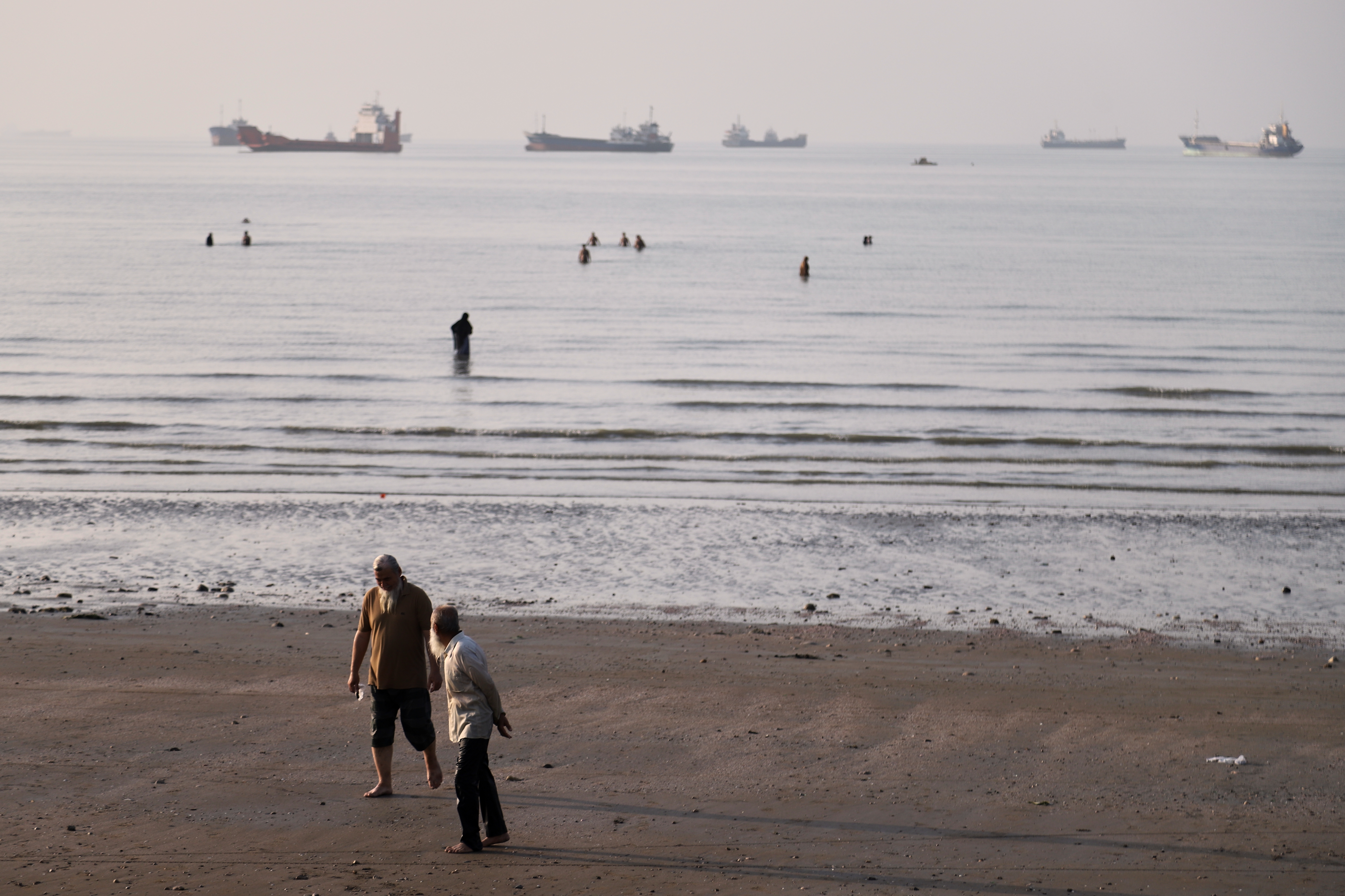 Men walk on the shoreline as people wade in the water in the Strait of Hormuz off Bandar Abbas, Iran, June 1, 2026.