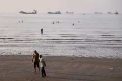 Men walk on the shoreline as people wade in the water in the Strait of Hormuz off Bandar Abbas, Iran, June 1, 2026.