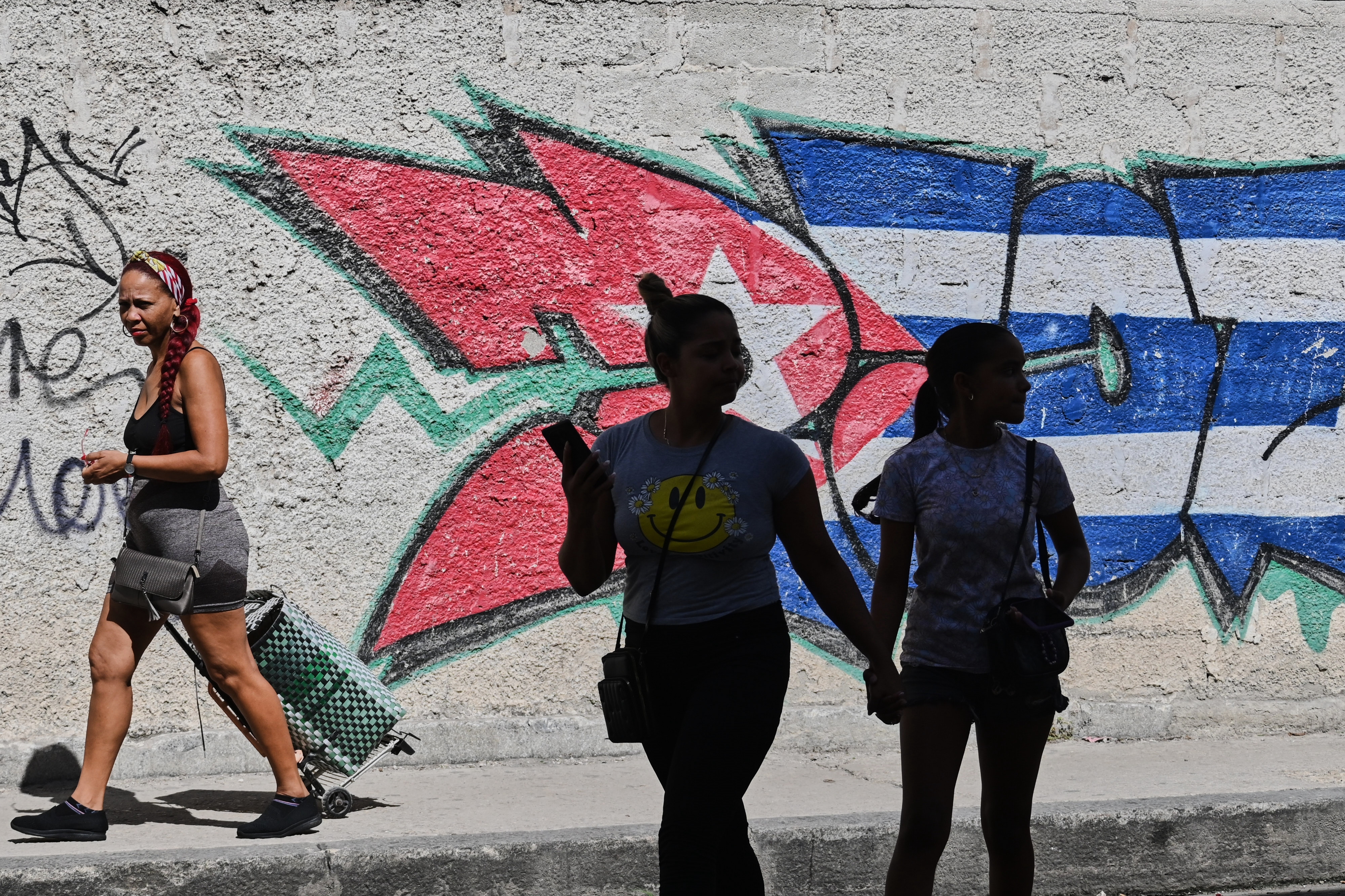 People walk past graffiti in the colors of the Cuban flag in Havana, June 17, 2026.