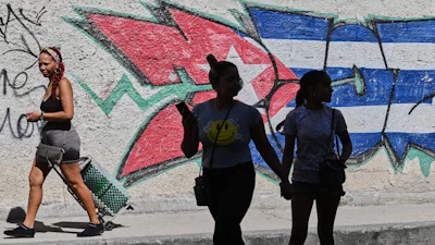 People walk past graffiti in the colors of the Cuban flag in Havana, June 17, 2026.