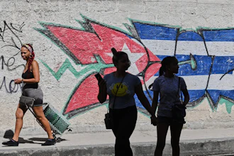 People walk past graffiti in the colors of the Cuban flag in Havana, June 17, 2026.