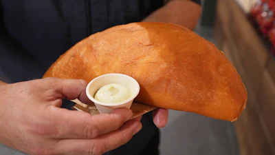 Lazaro Luya, the concession chef at Sol Cubano, displays the 'empanada mundial,' June 21, 2026, Miami Gardens, Fla.