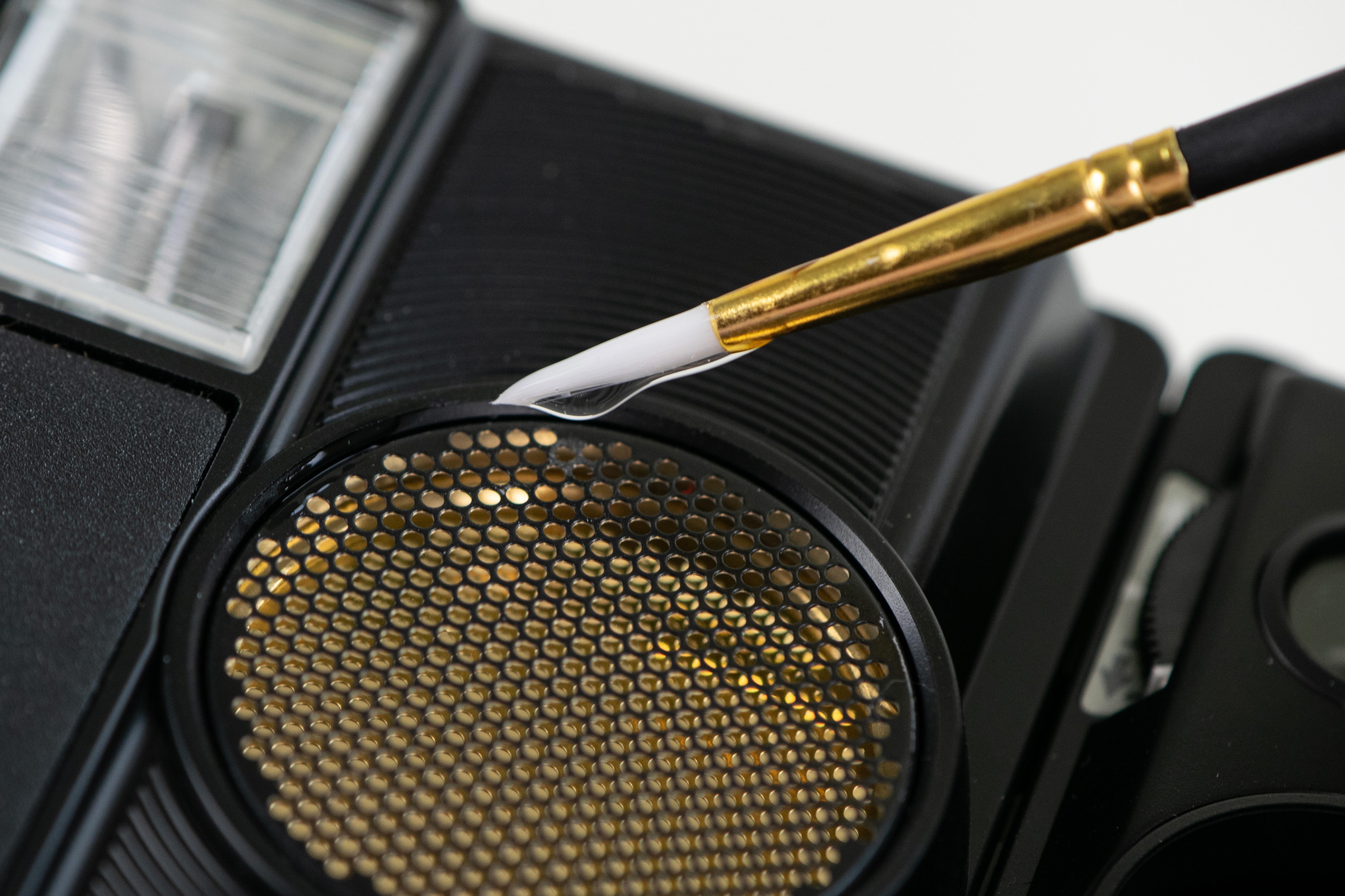 Gold makeup brush and eyeshadow palette with dotted texture on black cosmetic palette