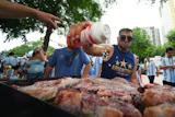 Lucas Martinez seasons meat with salt while grilling during a rally in Dallas, June 21, 2026.