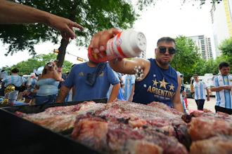 Lucas Martinez seasons meat with salt while grilling during a rally in Dallas, June 21, 2026.