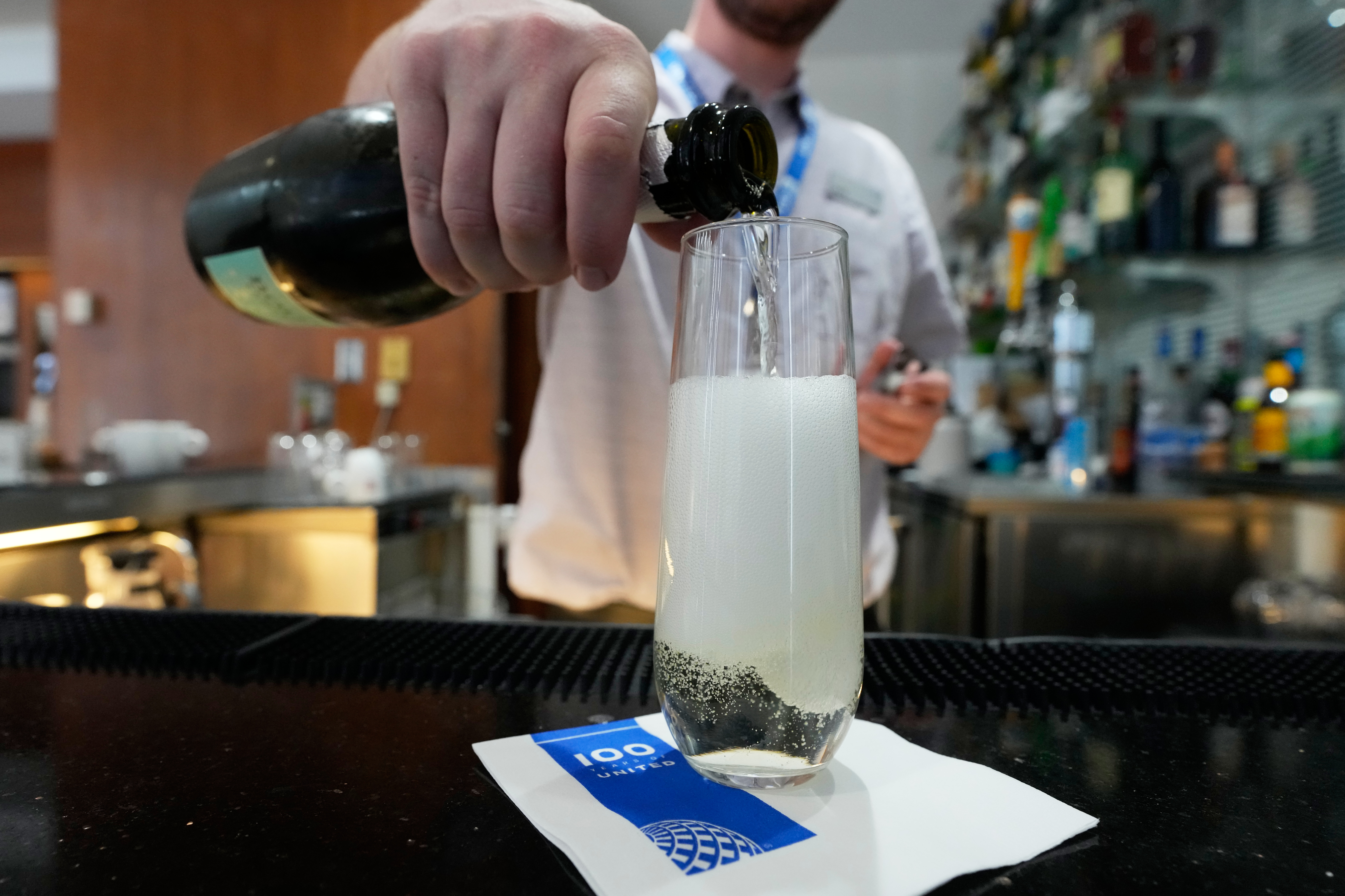 A bartender pours a glass of sparkling wine at the United Club lounge in Minneapolis, June 29, 2026.