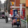 Akiko Sugaya blows a horn while she peddles tofu, prepared food and beverages in a cart in Tokyo, July 4, 2026.